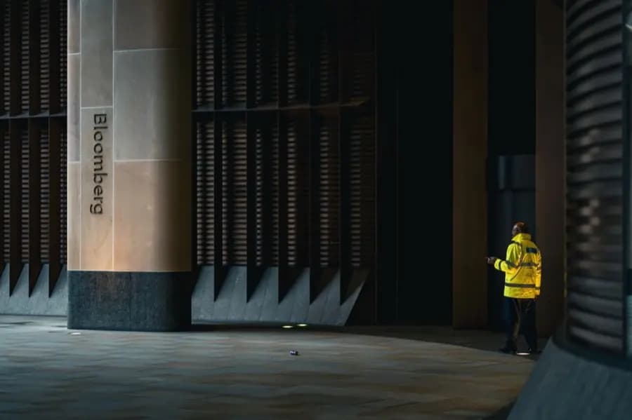 A security officer in a high-visibility jacket on duty outside an office building in London at night